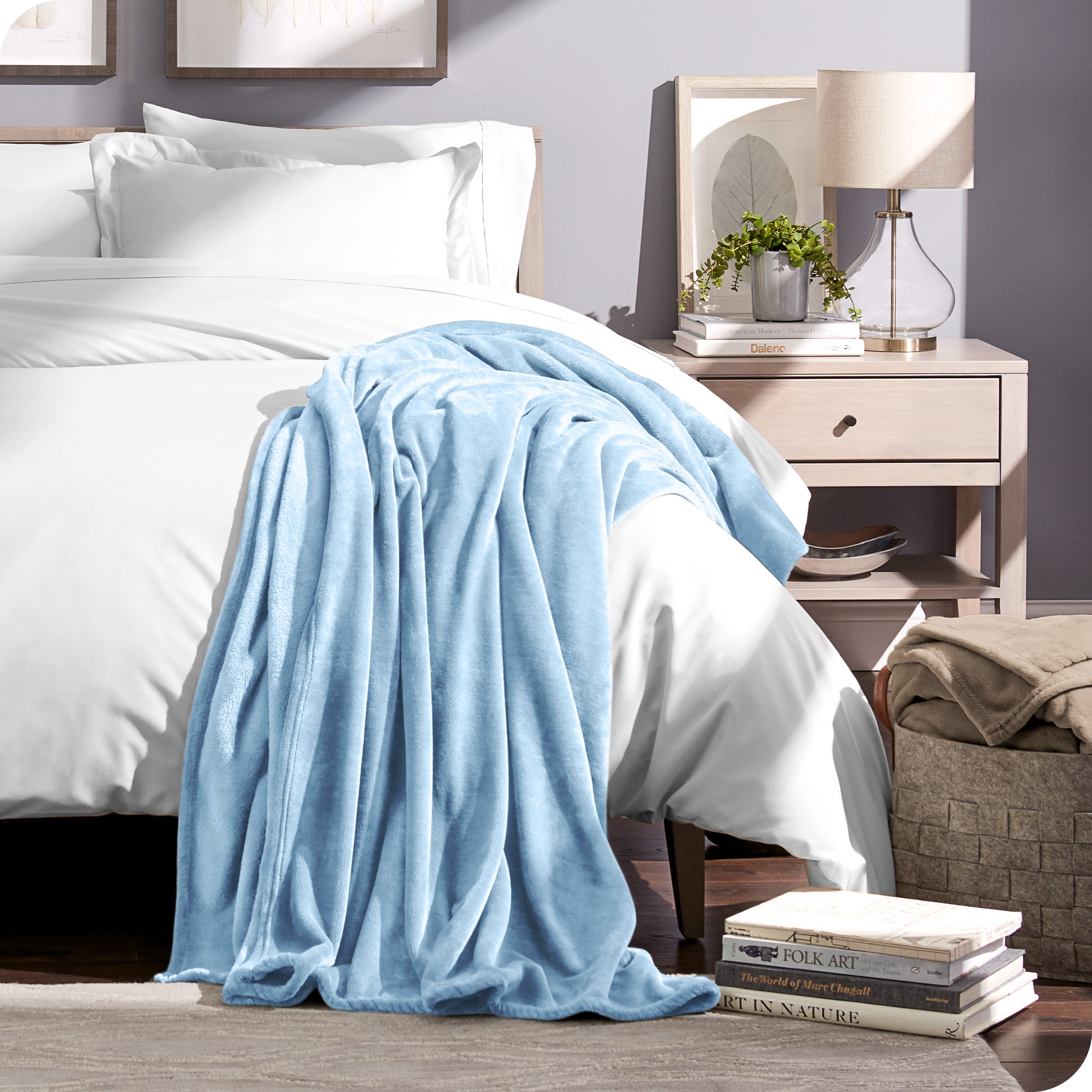 Microplush blanket draped over the end and side of a bed made with all white bedding. 