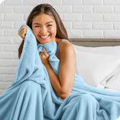 Woman sitting on a bed cuddling with a microplush blanket