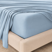 Fitted sheet and top sheet on a mattress with a beige bed frame