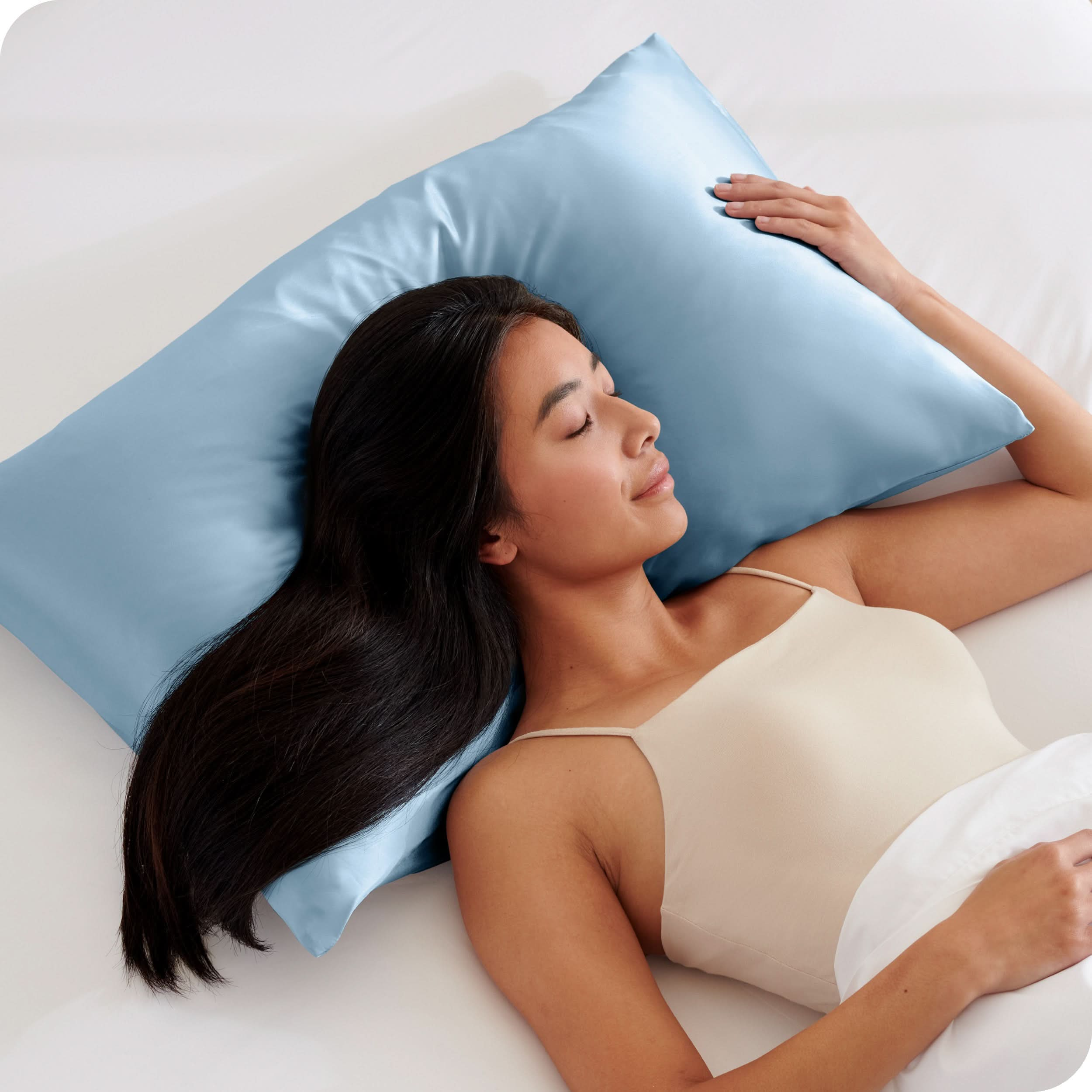 A woman is sleeping on a pillow with a satin pillowcase