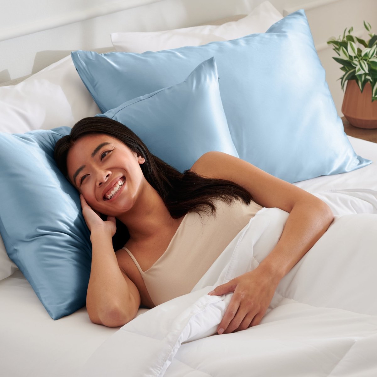Woman lying on a bed with satin pillows and white bedding
