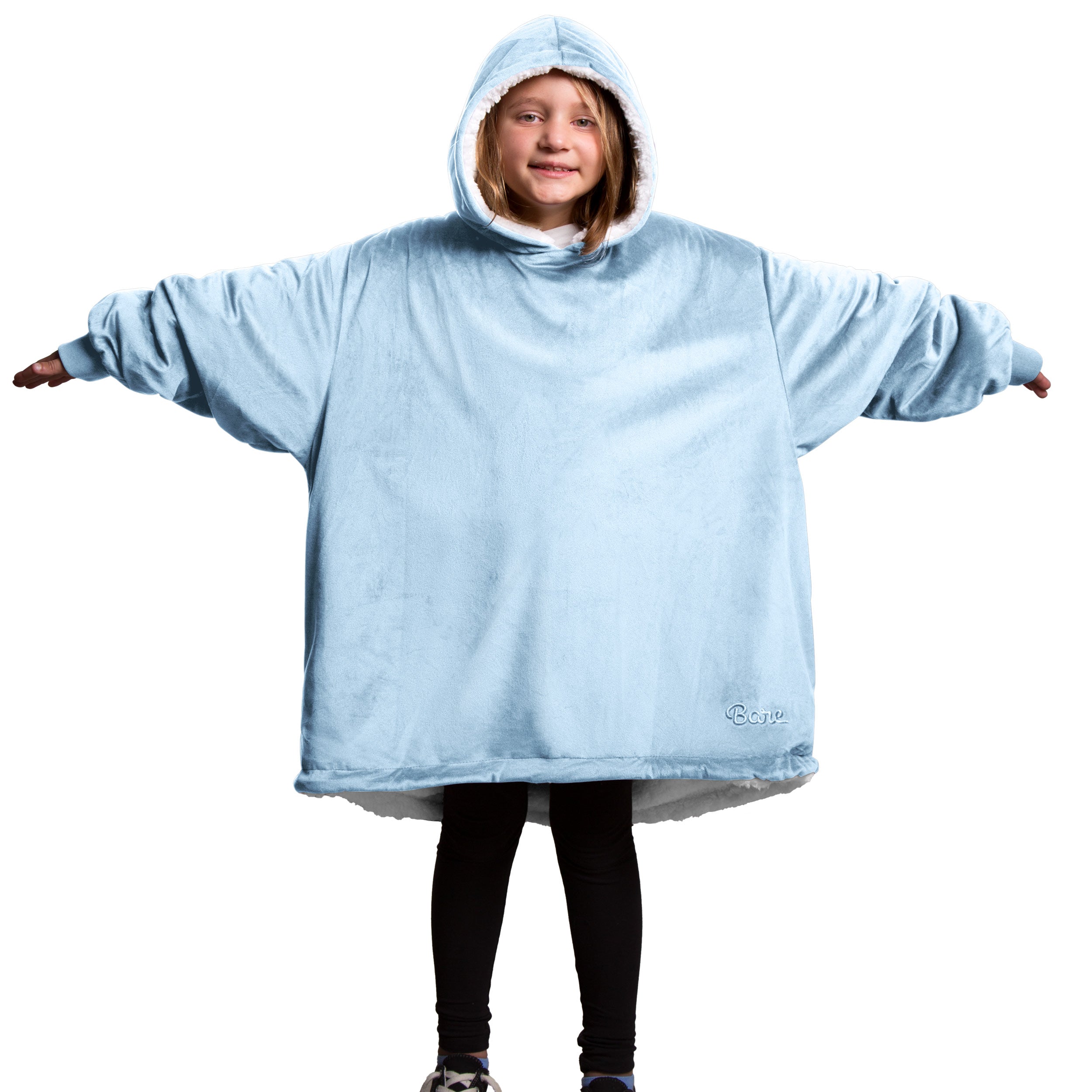 A child is wearing a sherpa wearable blanket and is standing with her arms stretched out.