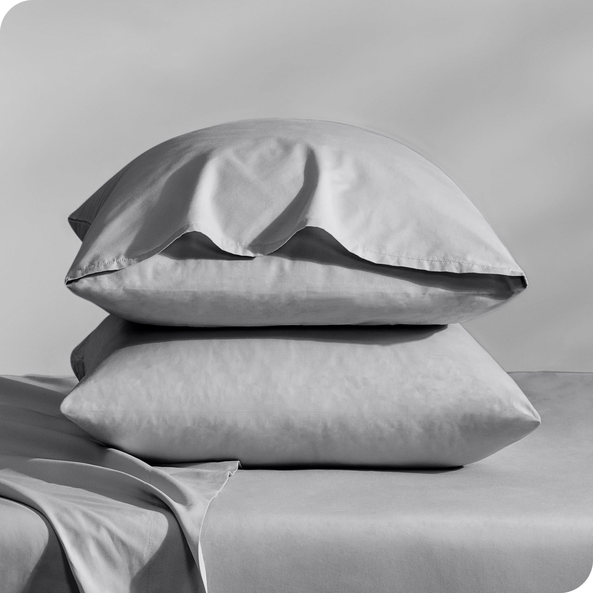 Pillows inside percale pillowcases stacked on a bed
