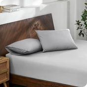 Diagonal view of modern wood bed with a fitted sheet and pillowcases

