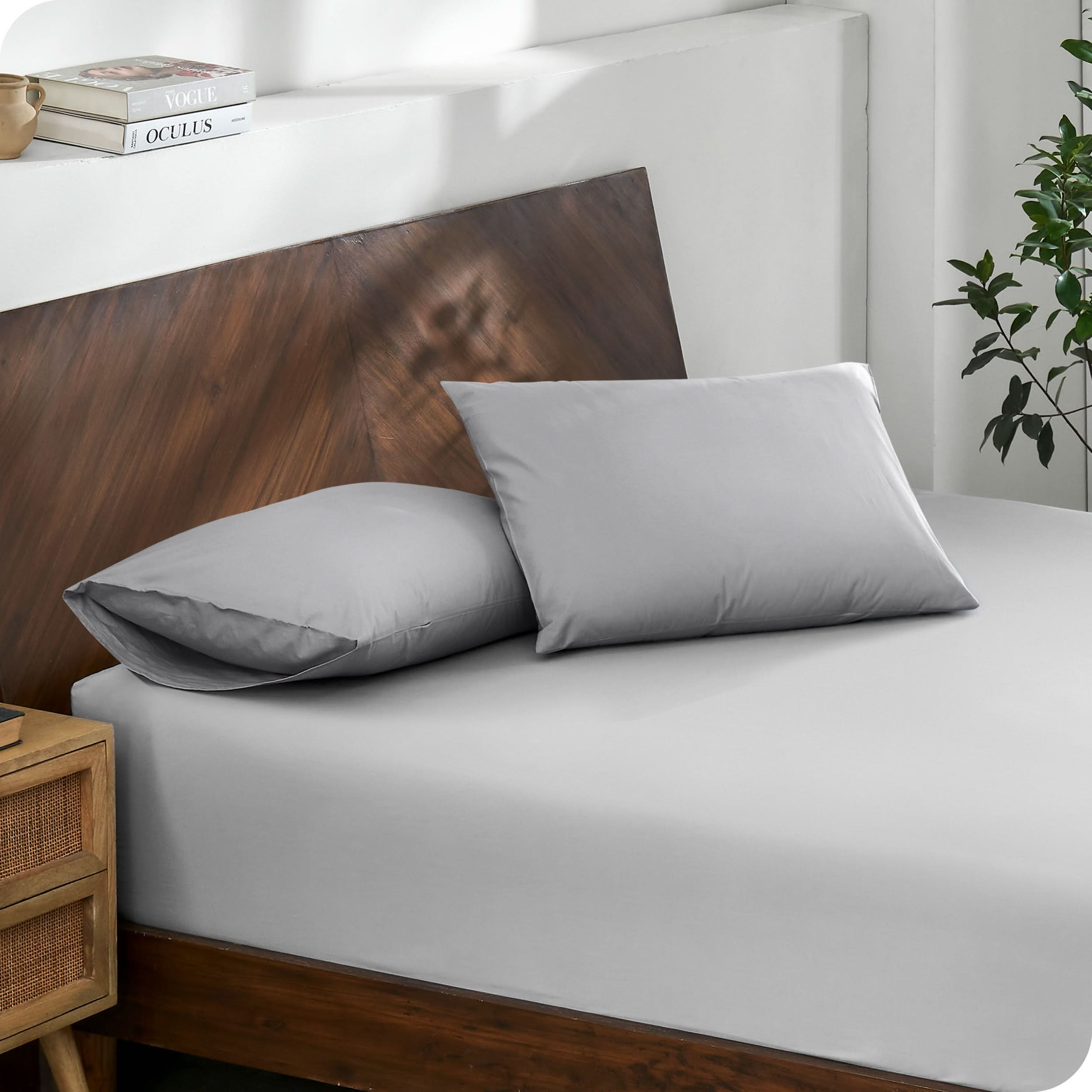 Diagonal view of modern wood bed with a fitted sheet and pillowcases

