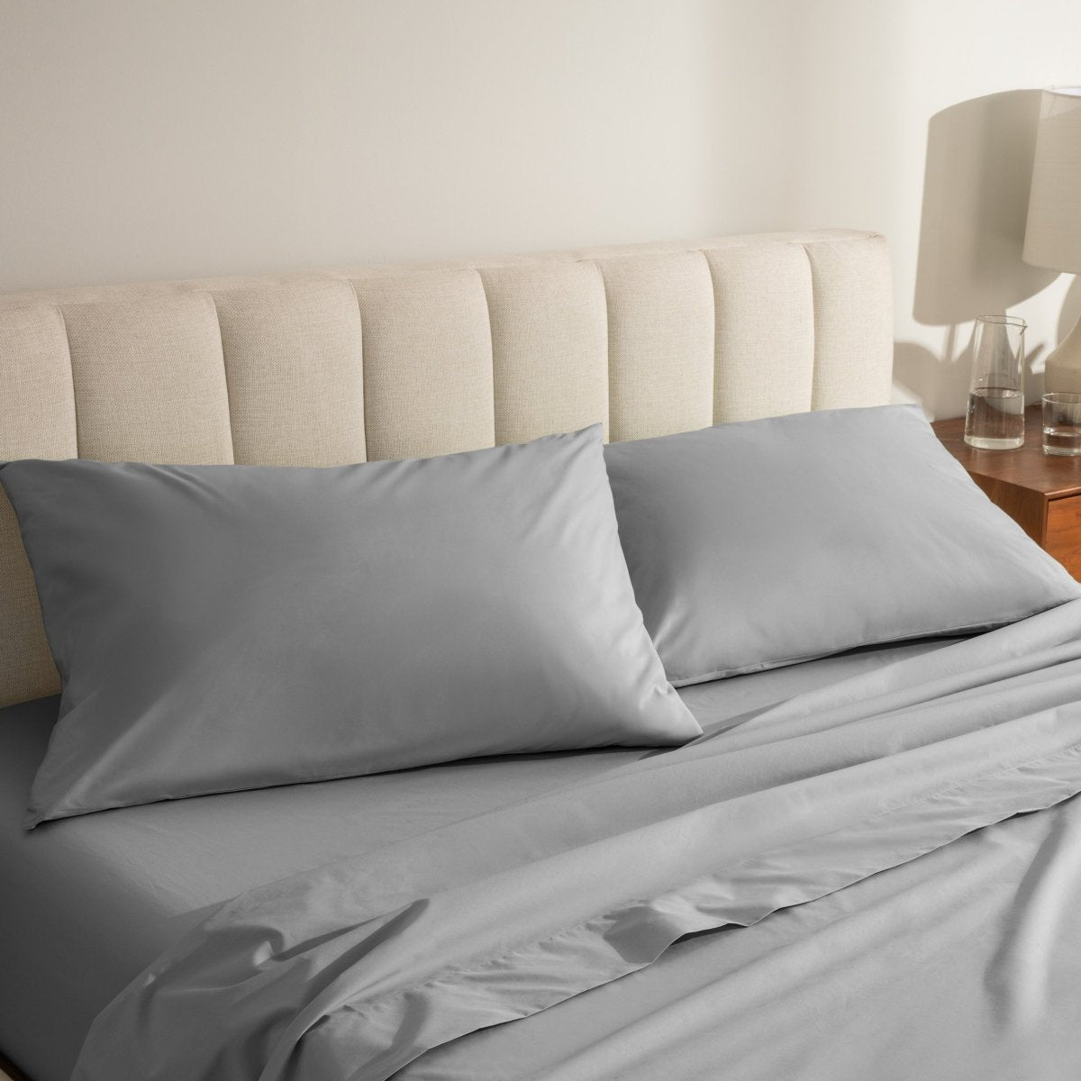 Percale bed sheets and pillowcases on a neatly made bed with a beige headboard.
