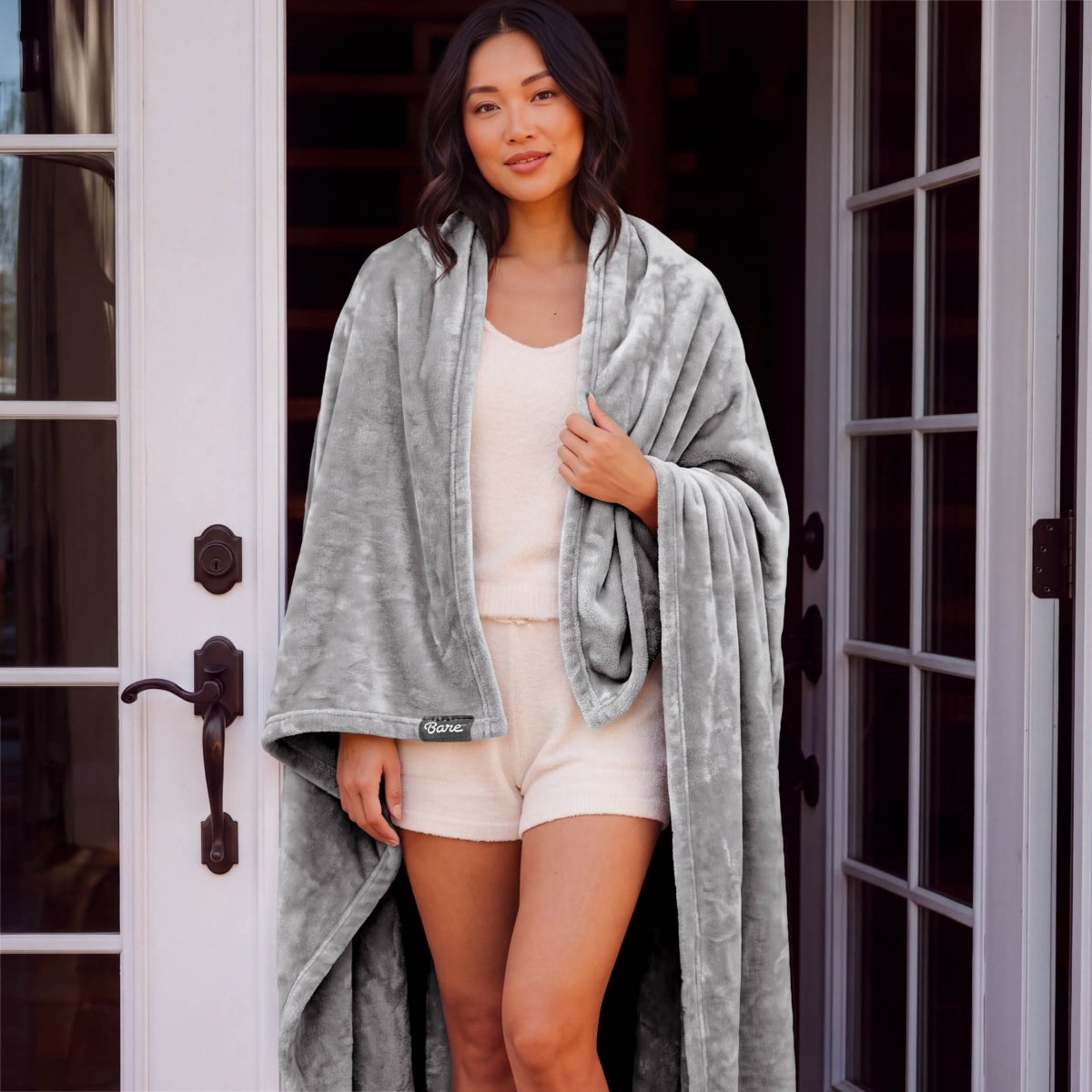 A woman standing with a microplush blanket wrapped around her