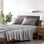 A bamboo sheet set draped over a bed with a wooden bed frame