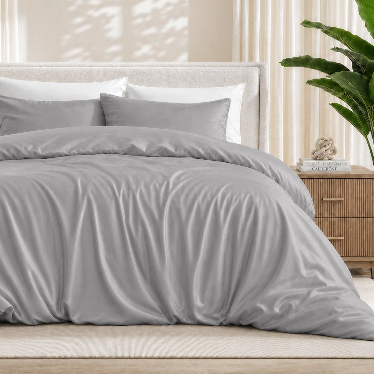 Light grey duvet cover set on a bed in a bedroom setting with a plant and nightstand.