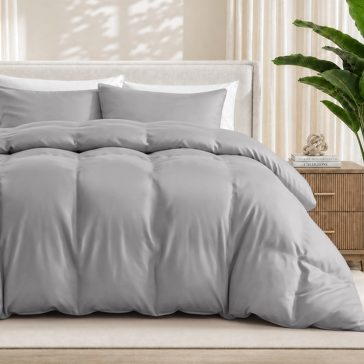 Light grey duvet cover set on a bed in a bedroom setting with a plant and nightstand.