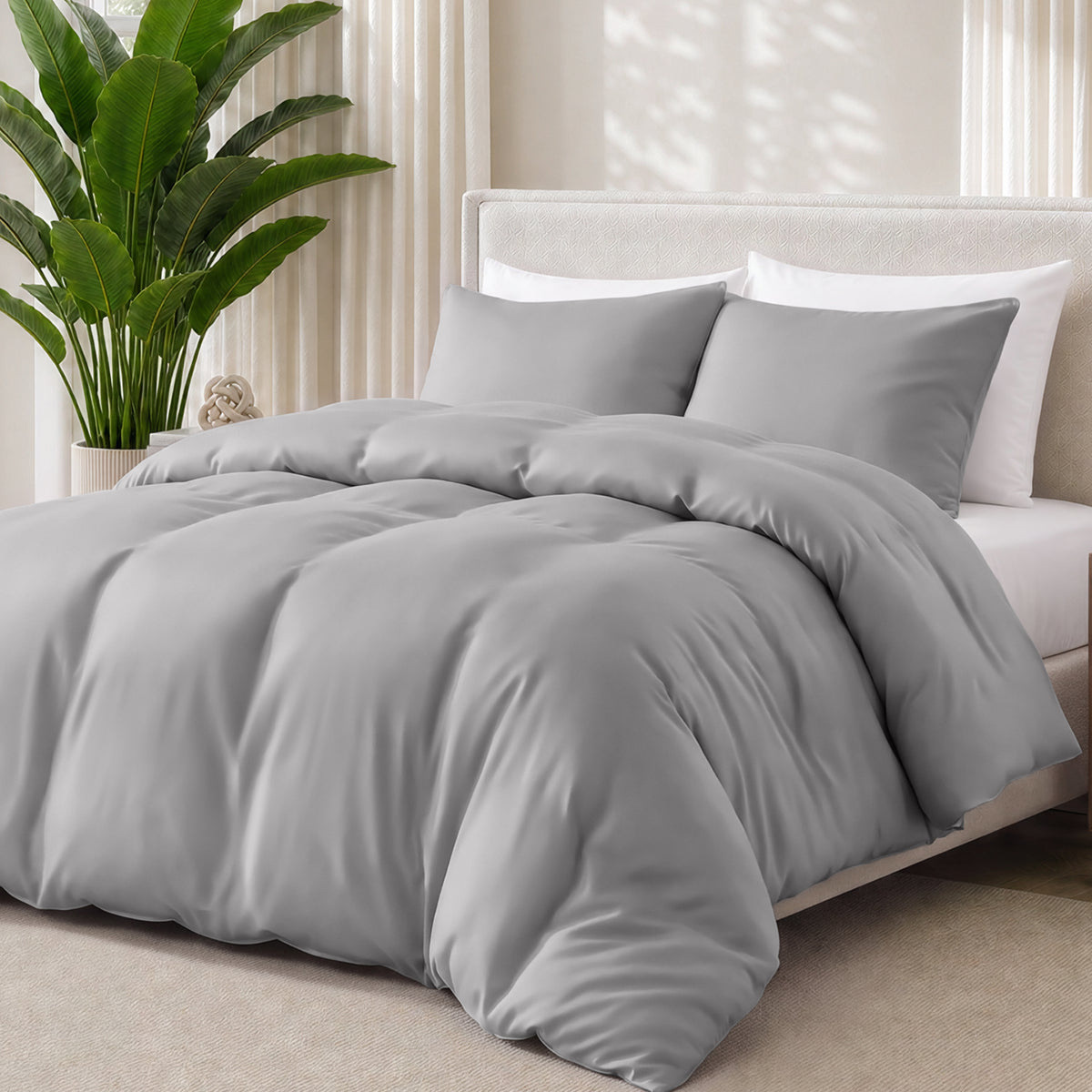 Light grey bedding set on a bed with a plant in the background