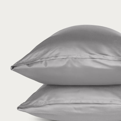Bamboo pillowcase and bedding against a woven headboard with a plant in the corner.