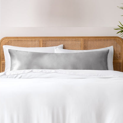 Pillows, sheets and a duvet cover on a bed with a wicker headboard and light gray bedding.