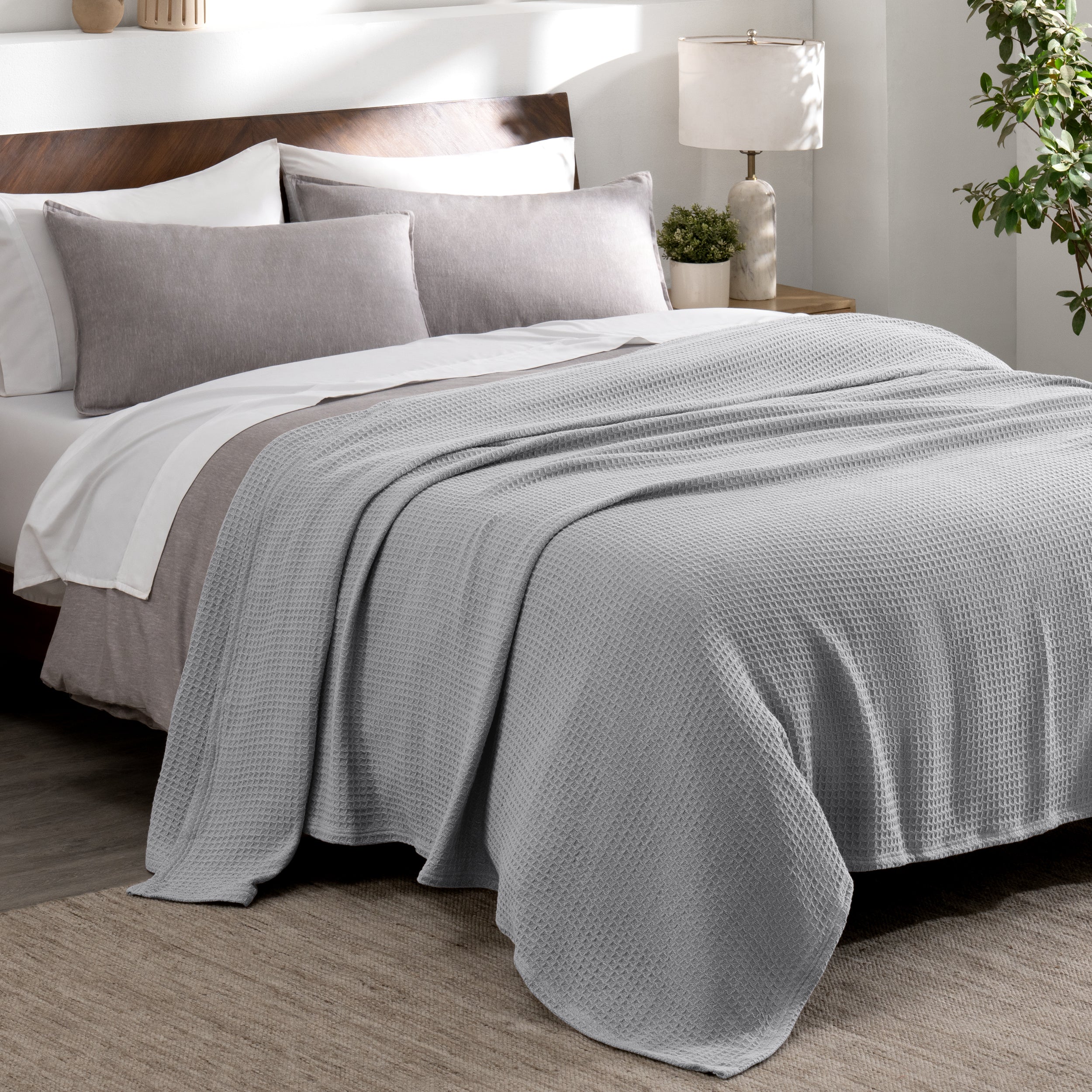 Cotton waffle blanket draped over a bed with pillows in a bedroom setting.