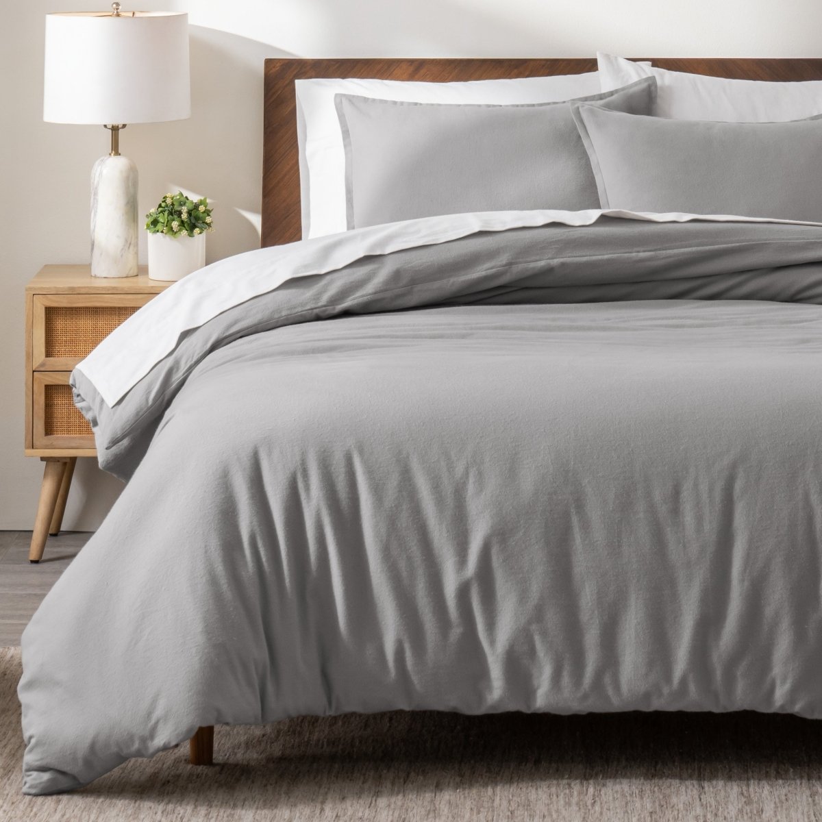 Flannel bedding set on a bed in a bedroom with a nightstand and lamp.