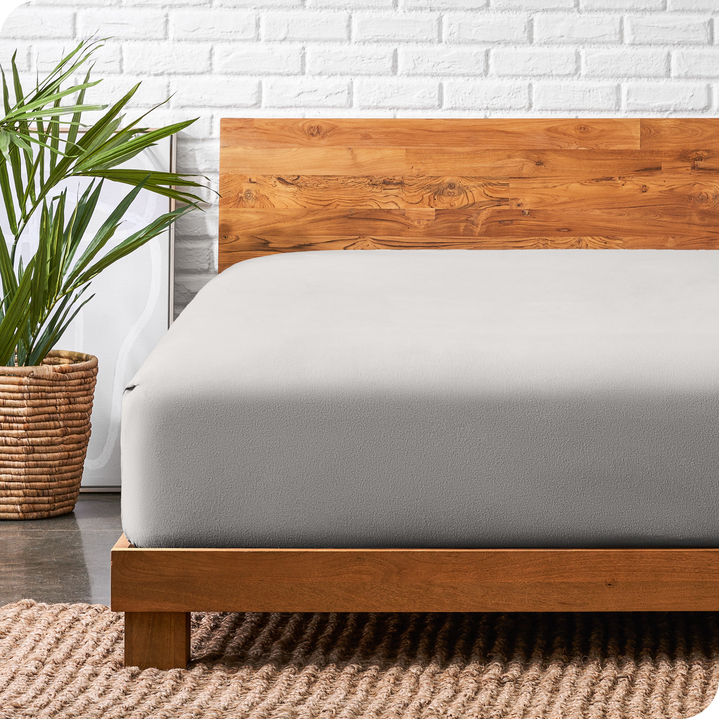 A modern bed with a wooden bed frame with a flannel fitted sheet on.