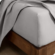 Corner of a bed with a flannel fitted sheet and top sheet on it