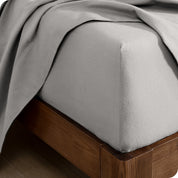 A close up of a corner of a modern bed with a flannel fitted sheet on.