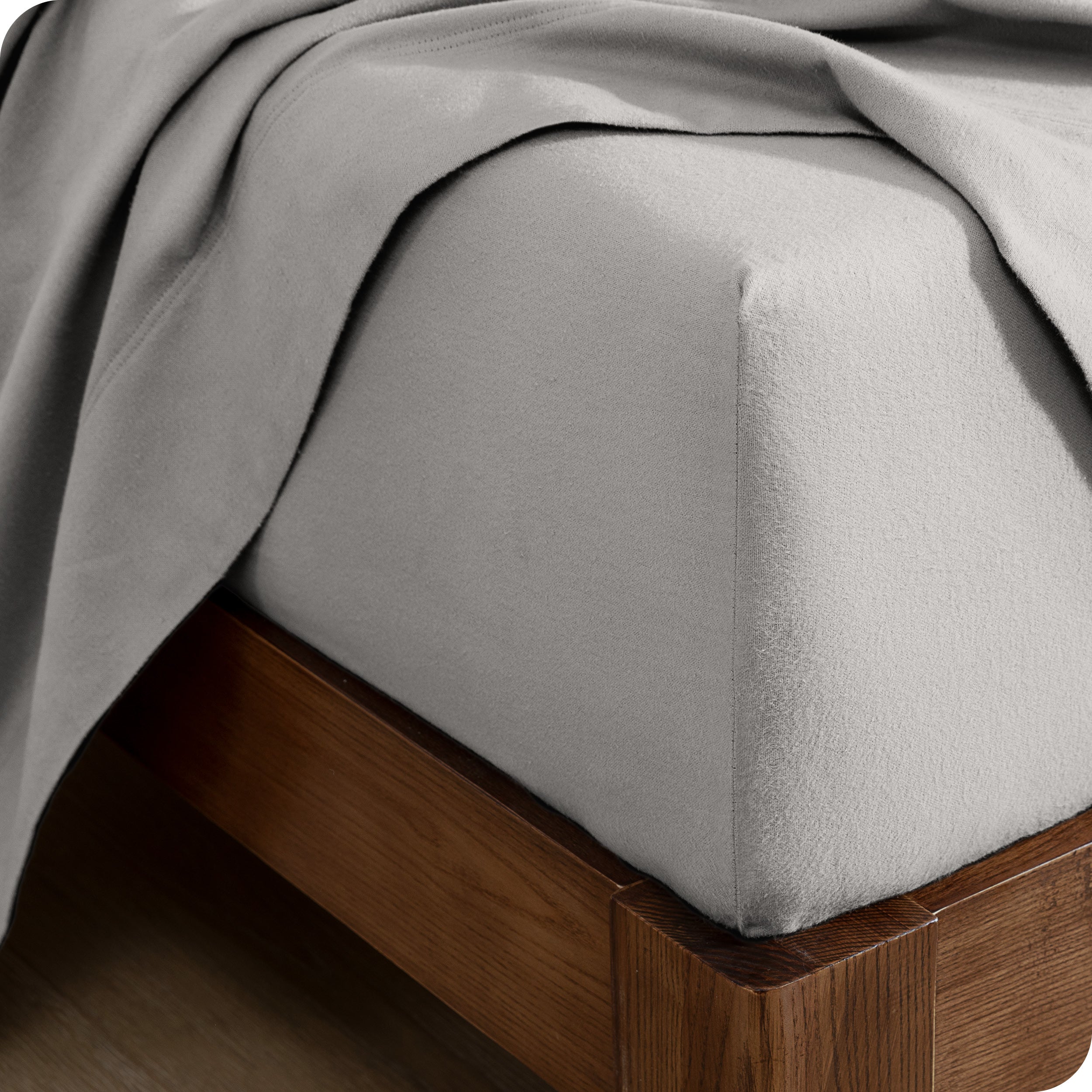 A close up of a corner of a modern bed with a flannel fitted sheet on.