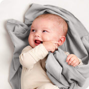 A baby lying on a receiving blanket. She has her thumb in her mouth.
