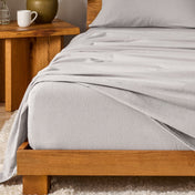 Bed with flannel bedding and wooden headboard and nightstand next to it.
