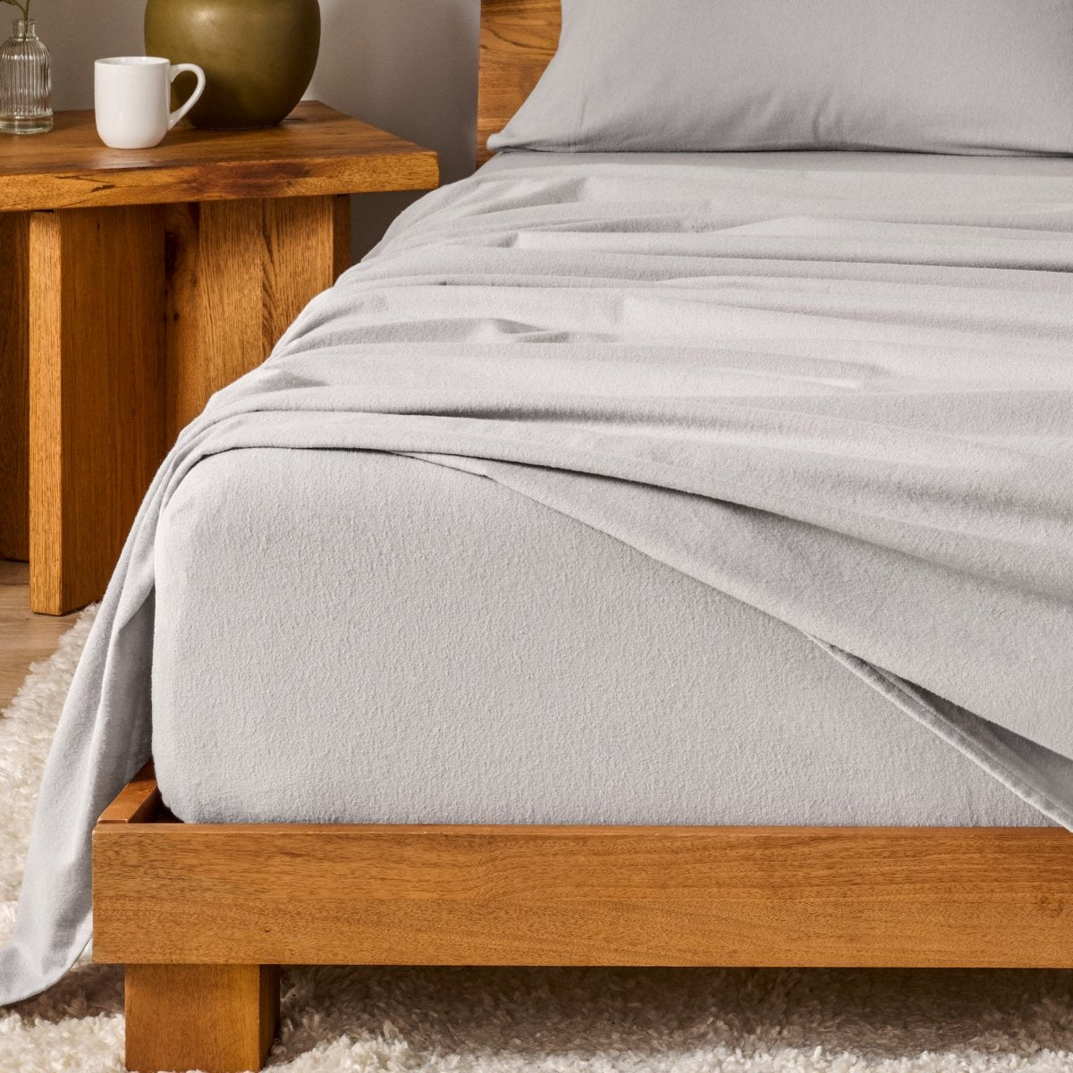 Bed with flannel bedding and wooden headboard and nightstand next to it.