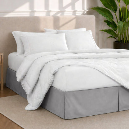 A modern bedroom with a bed skirt, comforter and sheets on the bed