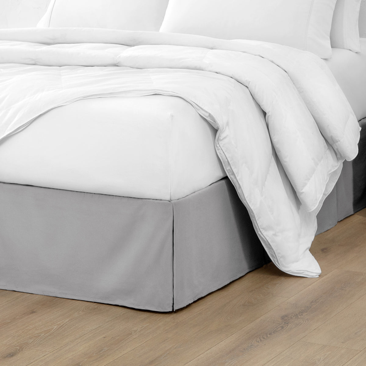Microfiber bed skirt on a bed with white bedding and wooden floor.
