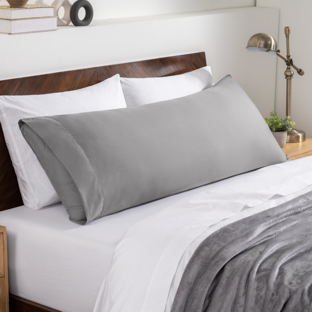 Bed sheets and pillows on a neatly made bed with a wooden headboard.