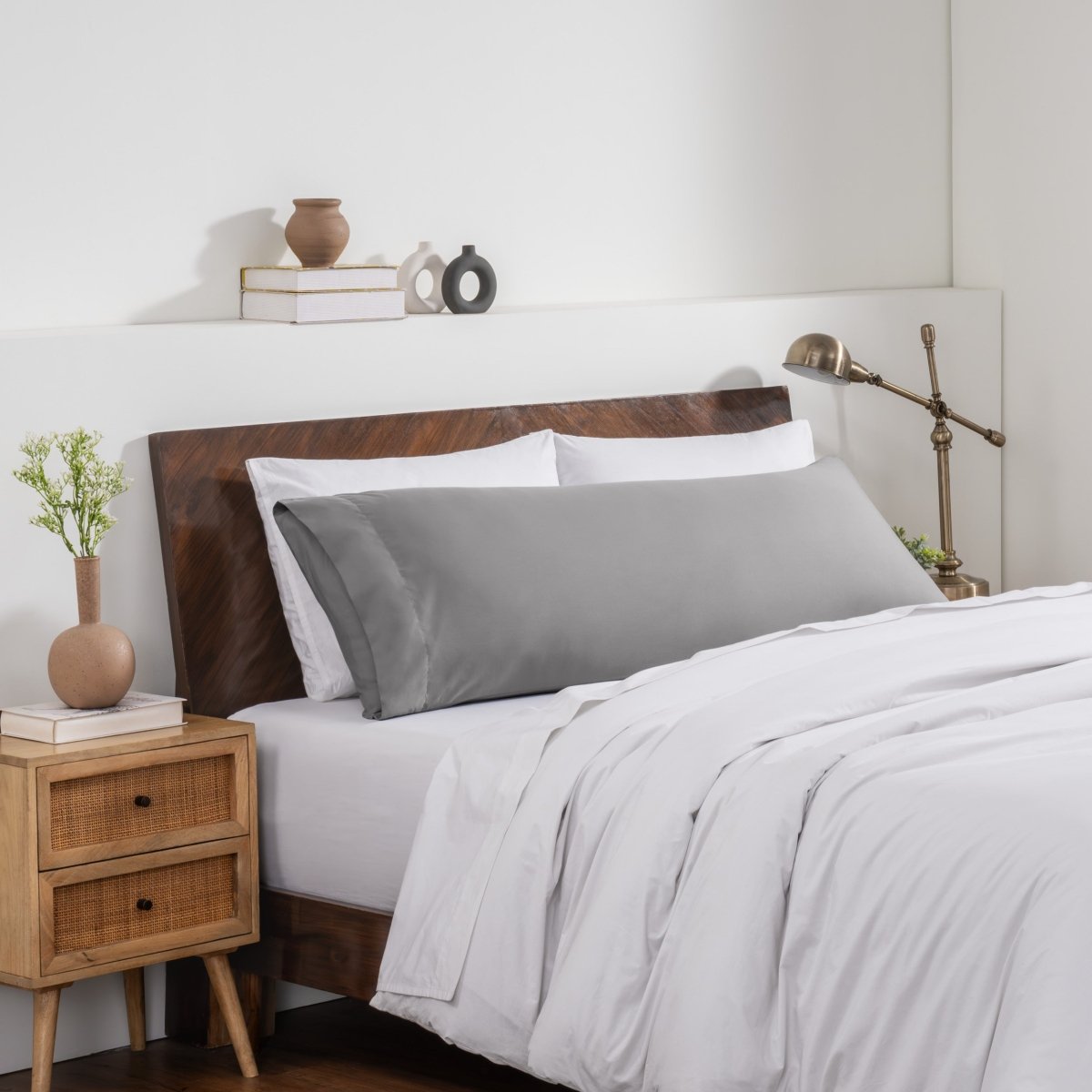 Bedroom with a wooden headboard and white bedding, featuring a nightstand and decorative items.
