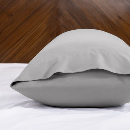 Body pillowcase with an envelope closure on a bed with a wooden headboard