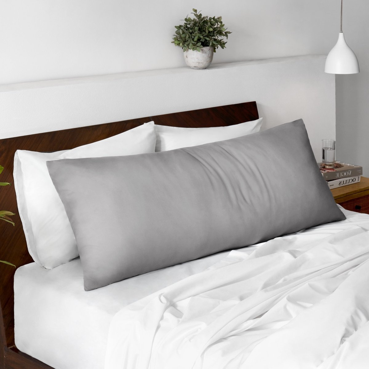 Body pillow on a bed with a wooden headboard and minimal decor.