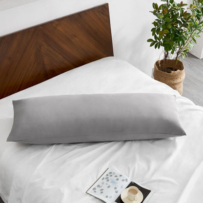 Pillowcase on a body pillow with a wooden headboard and plant in the background