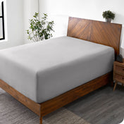 A diagonal view of a bed with just a fitted sheet on it