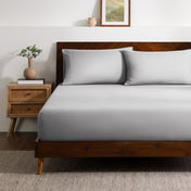 A bed made with a single fitted sheet and two matching pillowcases.