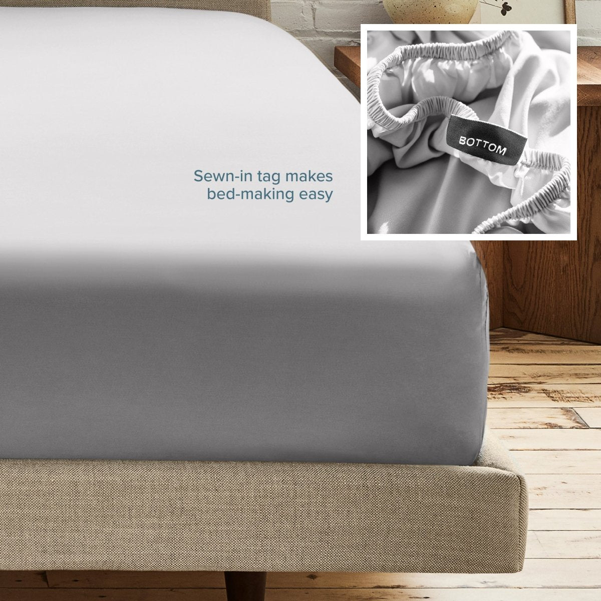 A fitted bed sheet on a bed frame with a small inset close-up of the elastic and a sewn-in tag labeled BOTTOM. White text on the sheet reads, 'Sewn-in tag makes bed-making easy.