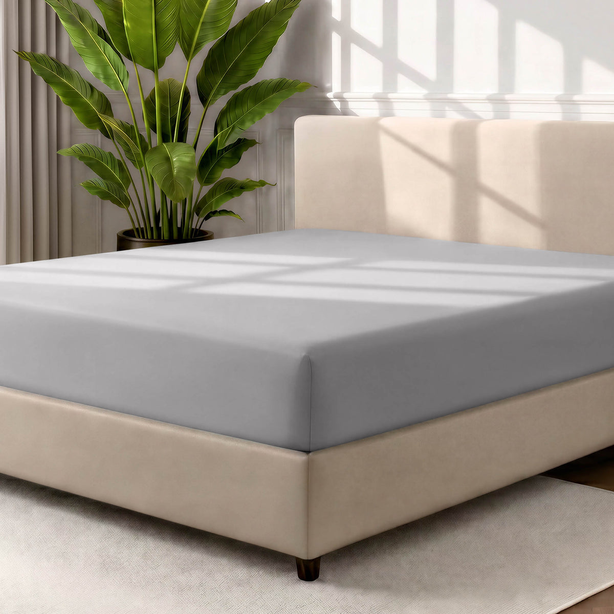 Man adjusting fitted sheet on a bed with white pillows.