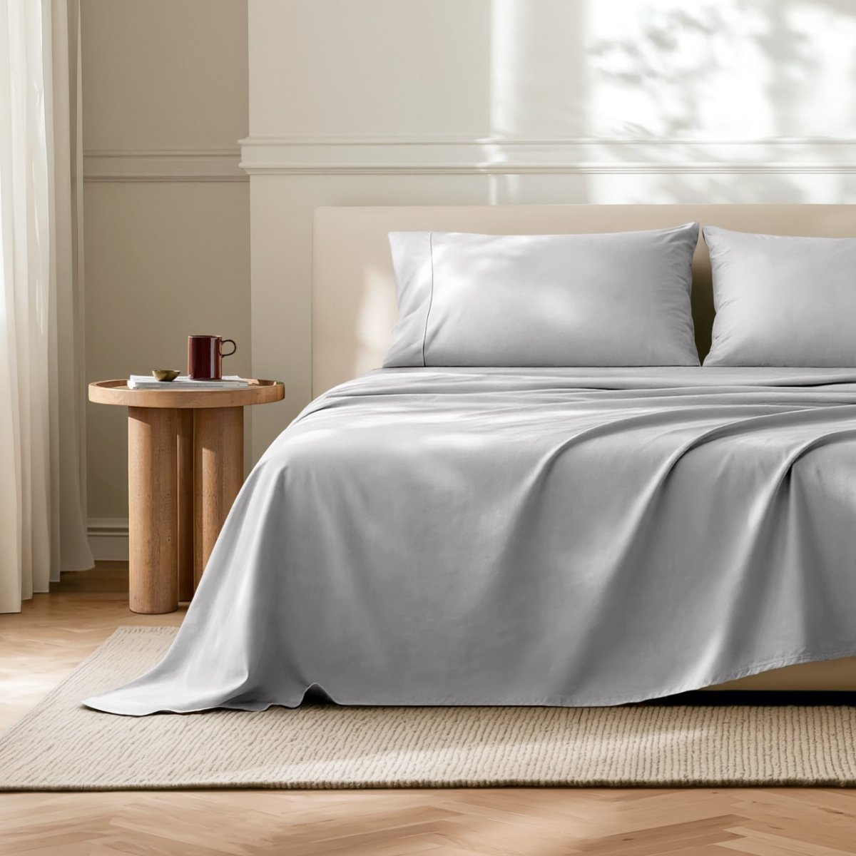 Microfiber flat sheet on a bed in a bedroom with a wooden side table.