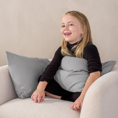 A child sitting while holding a microfiber pillowcase covered pillow