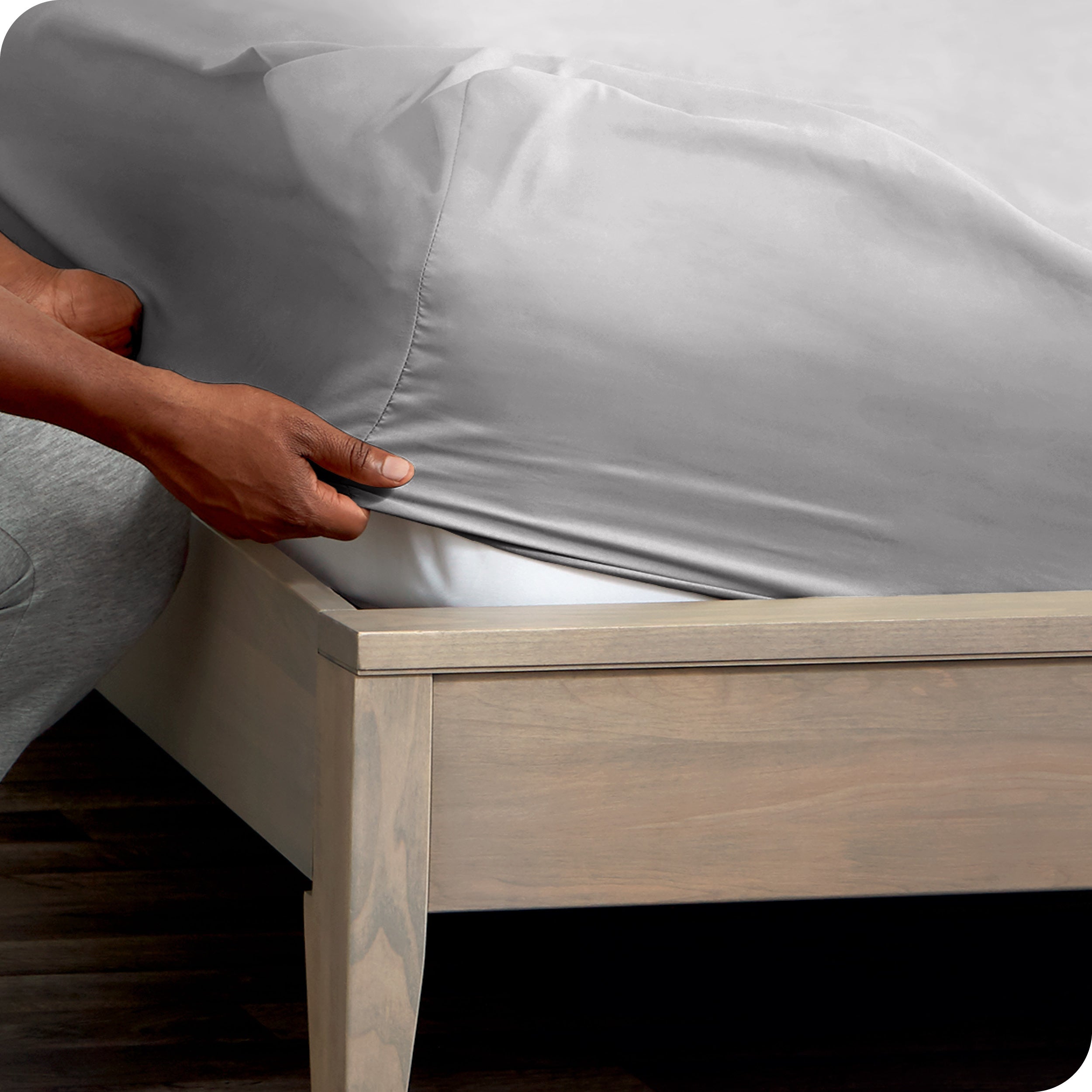 Person adjusting a fitted sheet on a mattress