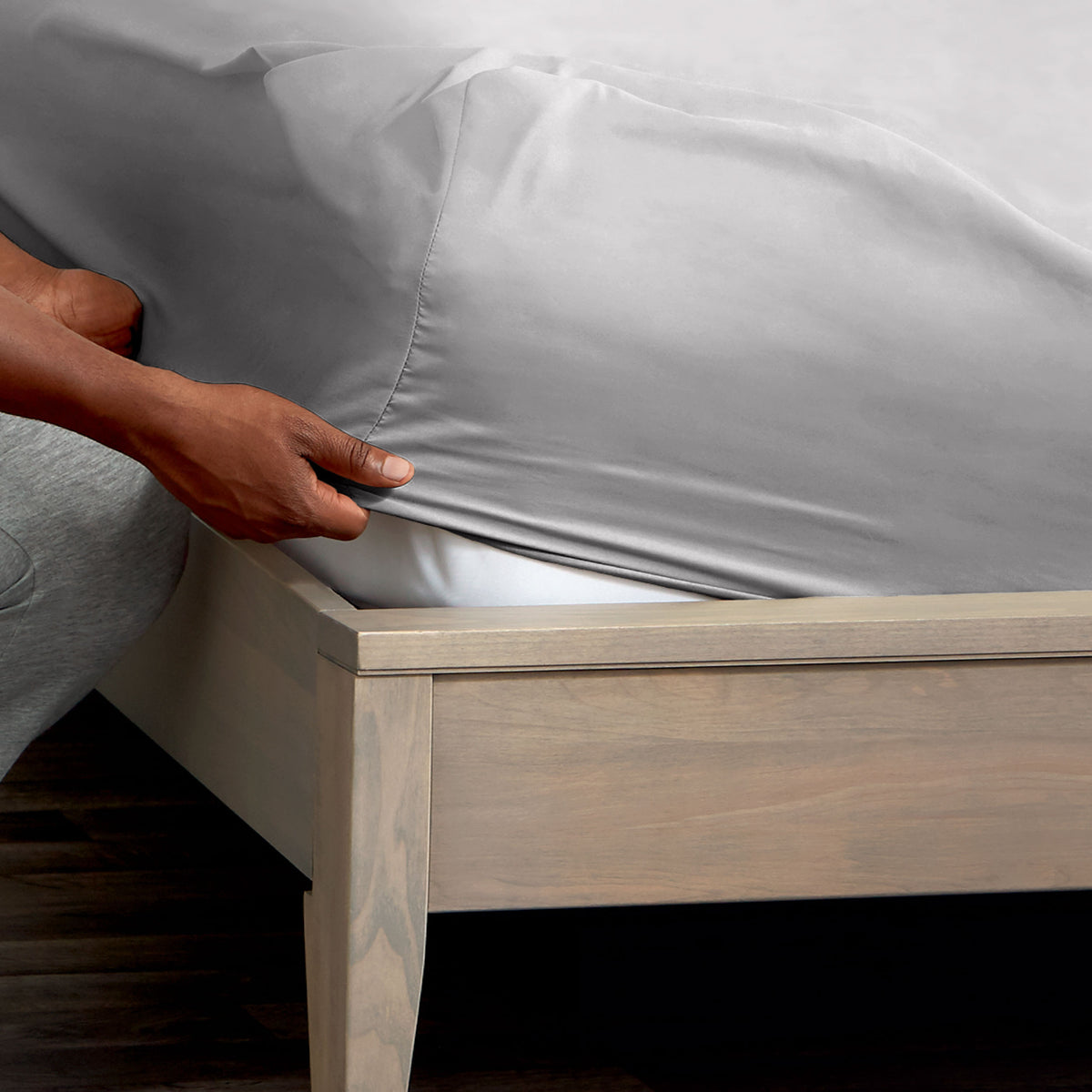 Person adjusting a fitted sheet on a mattress