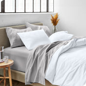 A modern bed made with a microfiber sheet set and duvet set. The duvet set and sheet set are folded over part way down the bed.