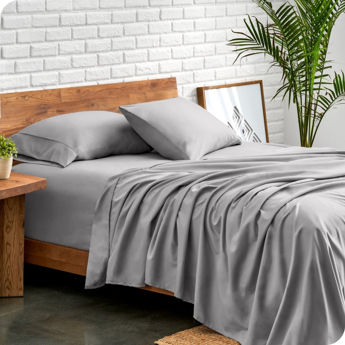 Bed with microfiber sheets against a white brick wall