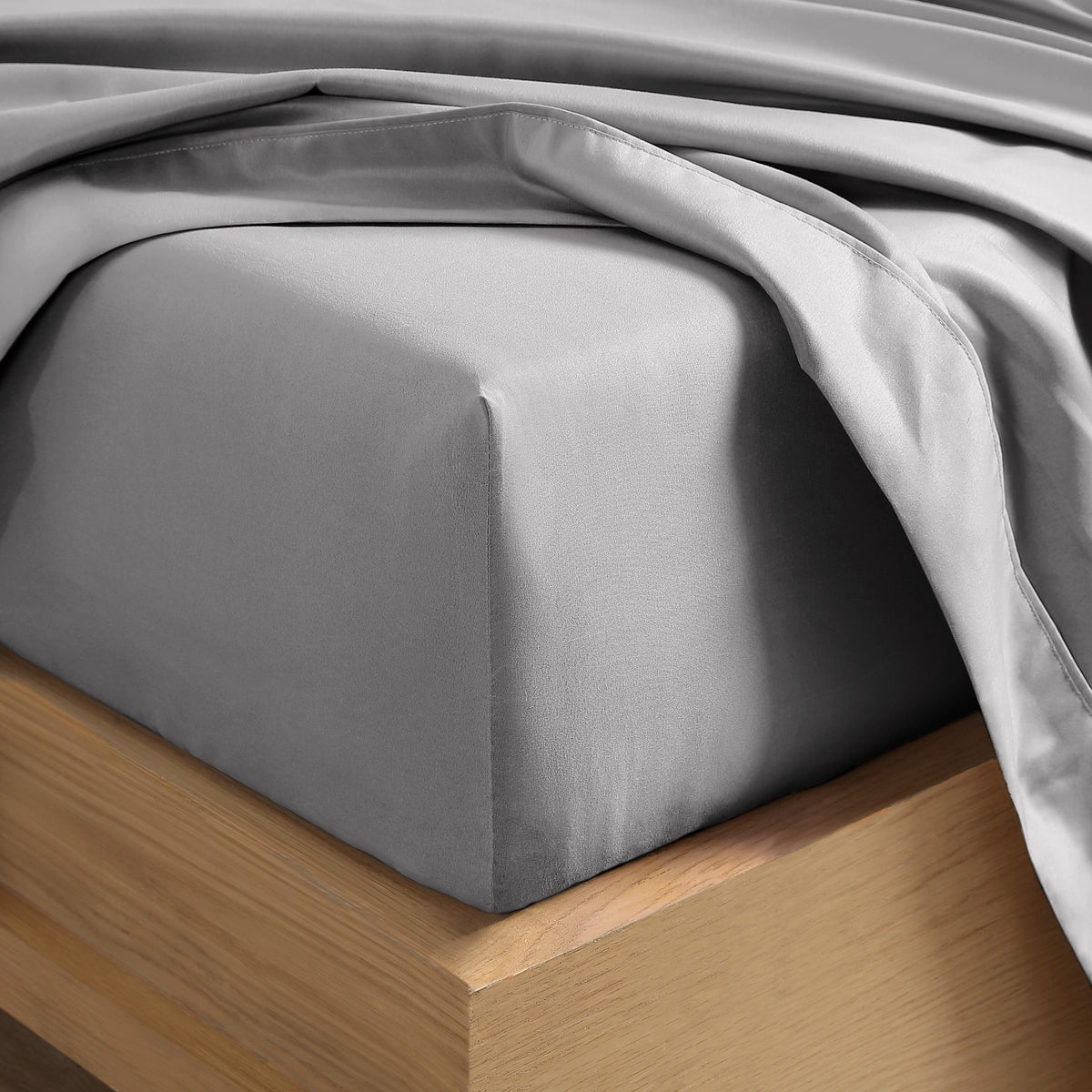 Close up of the corner of a mattress with a fitted sheet and flat sheet on it