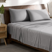 Microfiber stretch bed sheets and pillows on a wooden bed in a bedroom setting.