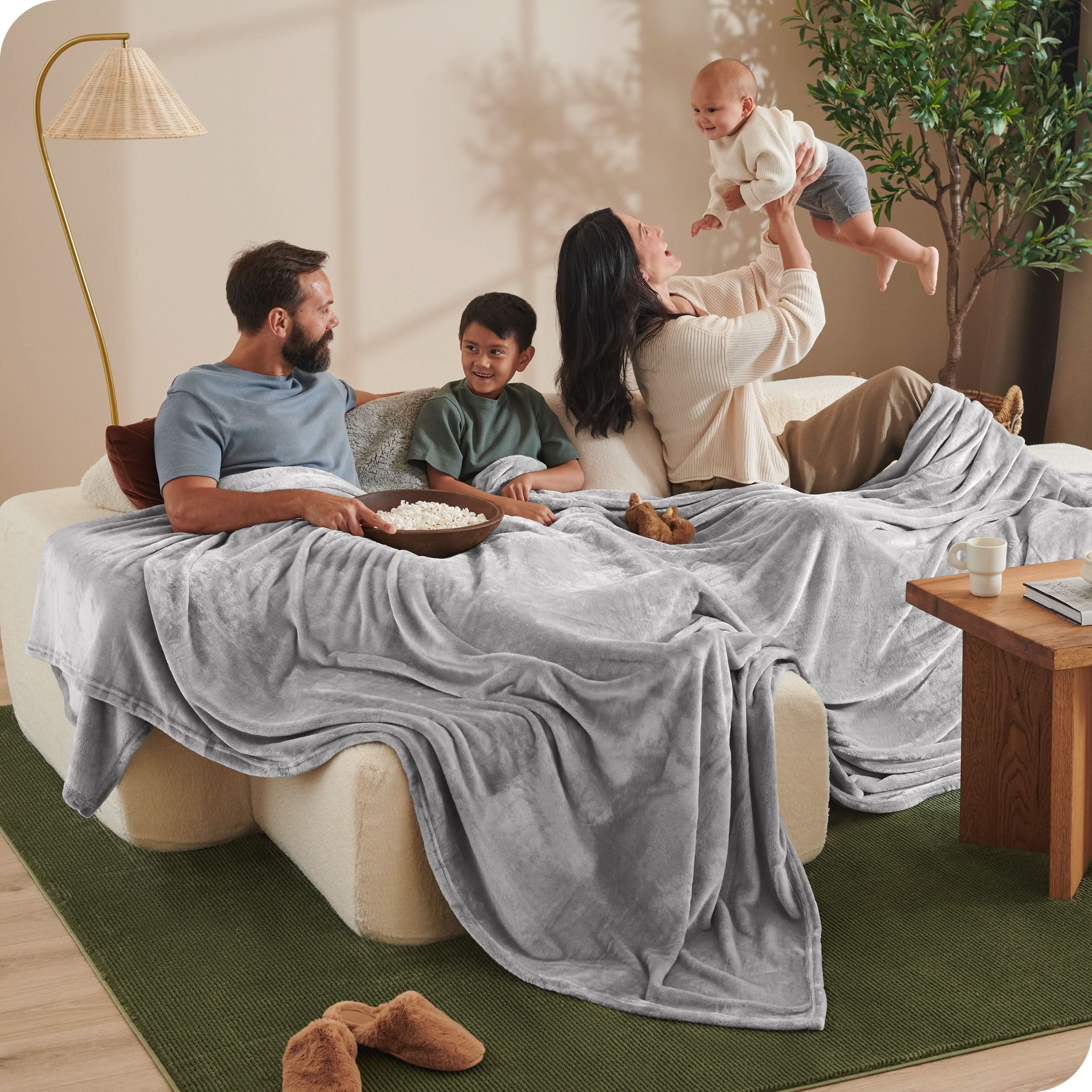 A family sitting with a giant microplush blanket covering them