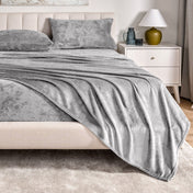 Microplush sheet set on a bed in a bedroom setting with a nightstand and lamp.