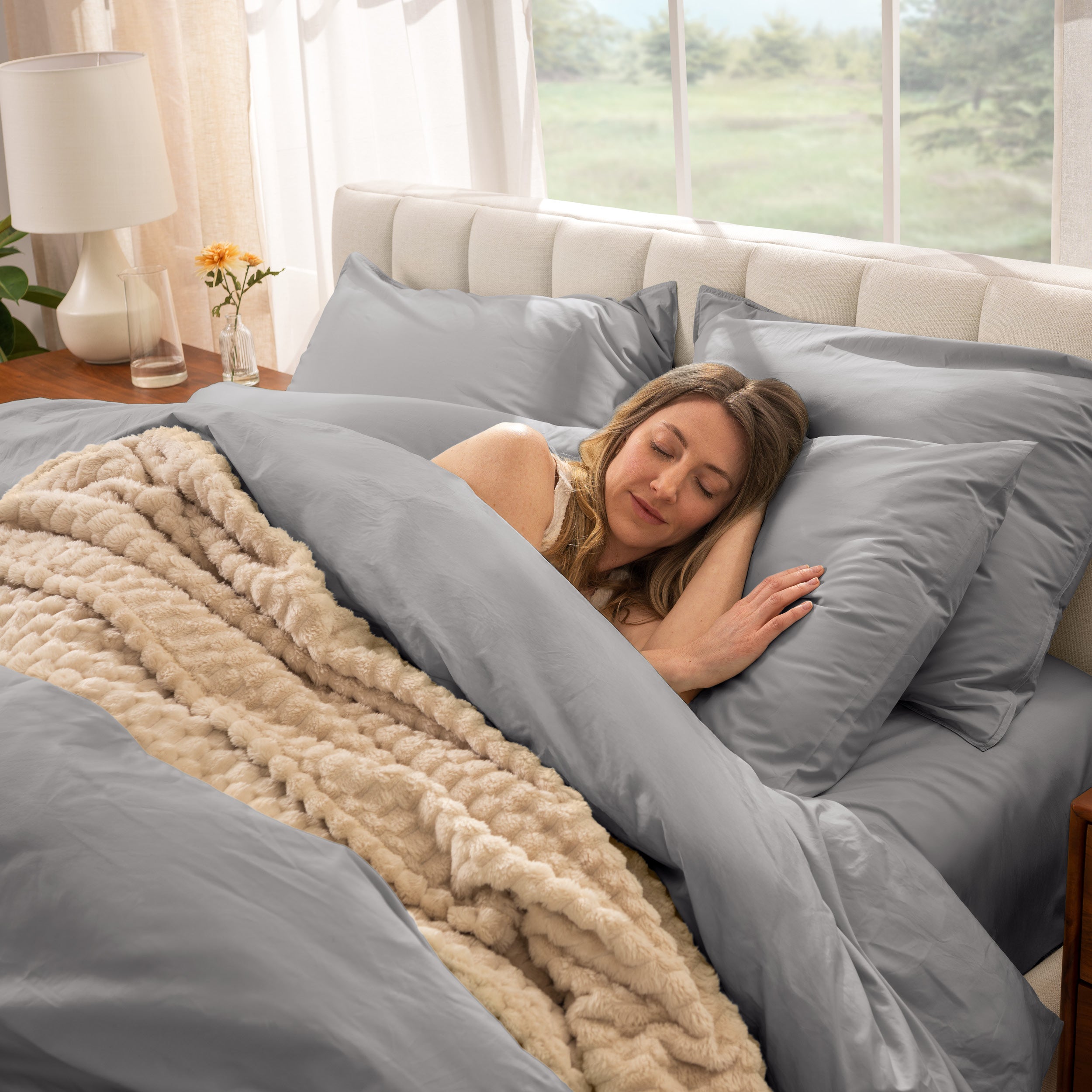 Woman sleeping in a bed with percale bedding and beige blanket