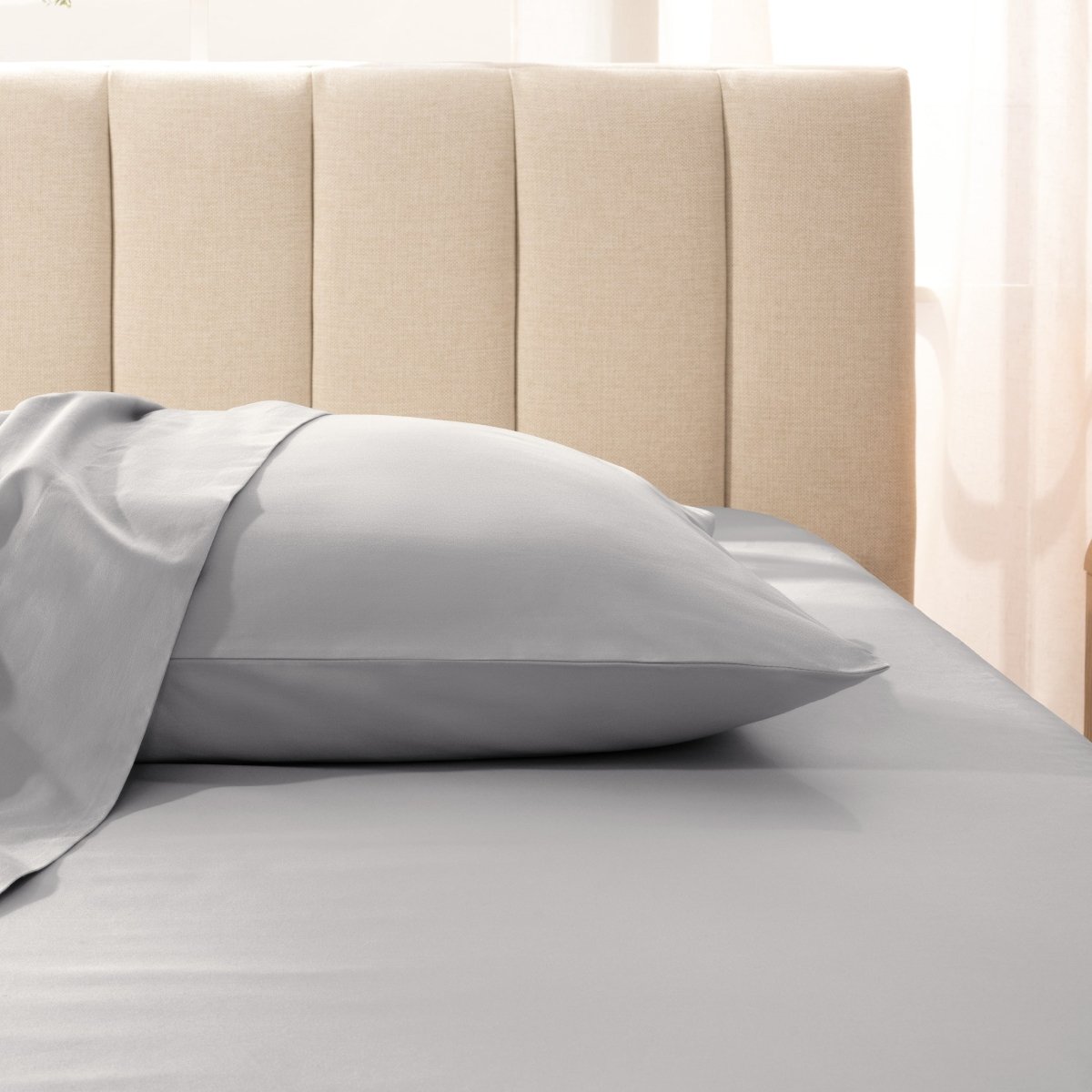 Sateen pillowcase on a bed with a beige headboard