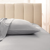 Sateen pillowcase on a bed with a beige headboard